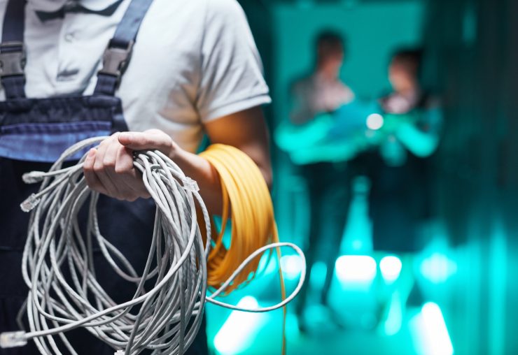 Close up of network engineer holding cables in server room during maintenance work in data center, copy space
